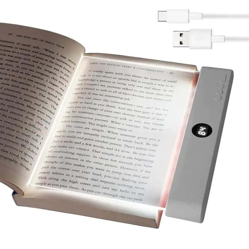 Book light illuminating an open book with a USB cable attached
